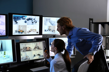 Security guards monitoring modern CCTV cameras in surveillance room