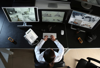 Security guard monitoring modern CCTV cameras in surveillance room