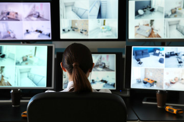 Security guard monitoring modern CCTV cameras in surveillance room