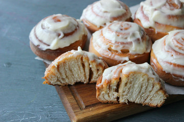 Beautiful fresh cinnamon rolls close-up on wooden grunge texture table. Fragrant homemade cakes, Cinnabon. A Cup of tea on a white saucer, cinnamon sticks. Delicious Breakfast buffet.