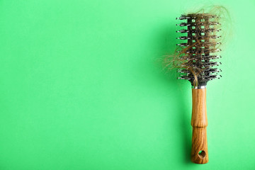 Brush with fallen down hair on color background