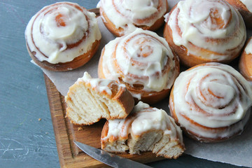 Beautiful fresh cinnamon rolls close-up on wooden grunge texture table. Fragrant homemade cakes, Cinnabon. A Cup of tea on a white saucer, cinnamon sticks. Delicious Breakfast buffet.