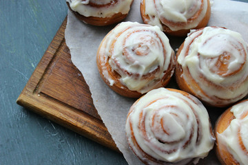Beautiful fresh cinnamon rolls close-up on wooden grunge texture table. Fragrant homemade cakes, Cinnabon. A Cup of tea on a white saucer, cinnamon sticks. Delicious Breakfast buffet.