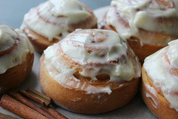 Beautiful fresh cinnamon rolls close-up on wooden grunge texture table. Fragrant homemade cakes, Cinnabon. A Cup of tea on a white saucer, cinnamon sticks. Delicious Breakfast buffet.