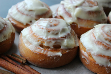 Beautiful fresh cinnamon rolls close-up on wooden grunge texture table. Fragrant homemade cakes, Cinnabon. A Cup of tea on a white saucer, cinnamon sticks. Delicious Breakfast buffet.