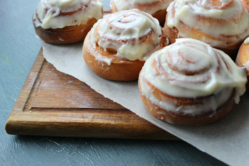 Beautiful fresh cinnamon rolls close-up on wooden grunge texture table. Fragrant homemade cakes, Cinnabon. A Cup of tea on a white saucer, cinnamon sticks. Delicious Breakfast buffet.