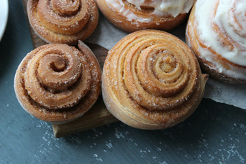 Beautiful fresh cinnamon rolls close-up on wooden grunge texture table. Fragrant homemade cakes, Cinnabon. A Cup of tea on a white saucer, cinnamon sticks. Delicious Breakfast buffet.