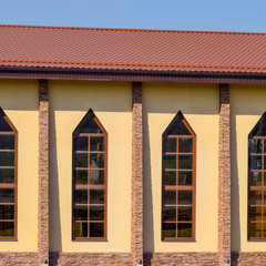 building with yellow walls and a red-brown roof. Modern material