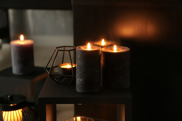 Beautiful burning candles on shelf in room