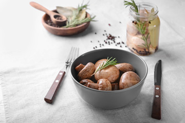 Bowl with tasty fermented mushrooms on light table