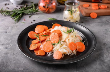 Plate with tasty fermented cabbage and carrot on grey table