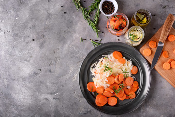 Plate with tasty fermented cabbage and carrot on grey table