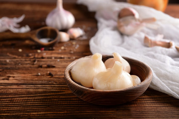 Plate with tasty fermented garlic on wooden table