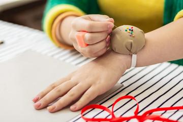 Pretty brunette asian dressmaker with bright nail polish taking a pin from a pin pillow