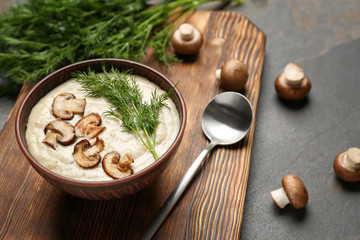 Bowl of tasty hot soup on wooden board