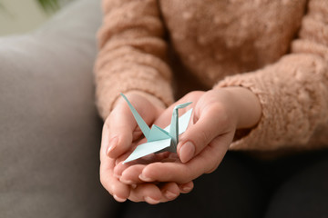 Young woman holding origami bird, closeup