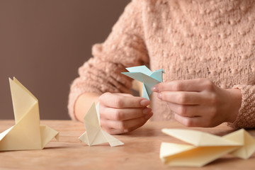 Young woman with origami bird at table, closeup
