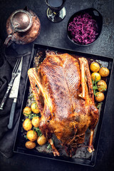 Traditional roasted stuffed Christmas duck with blue kraut and potatoes as top view on a board