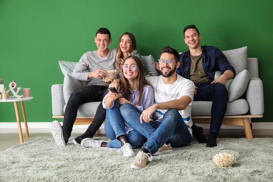 Friends eating popcorn and watching TV at home