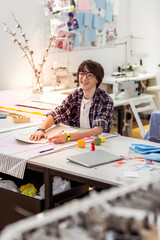 Young dark-haired asian designer with in eyeglasses smiling happily