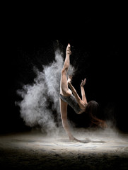 Obraz na płótnie Canvas Graceful woman doing splits dancing in white dust