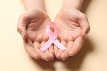 Female hands with pink ribbon on light background. Breast cancer awareness concept