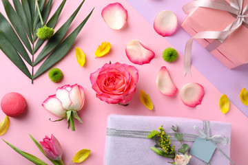 Composition with flowers, gift boxes and tropical leaf on color background