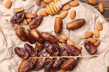 Sweet dried dates with almonds and honey dipper on table