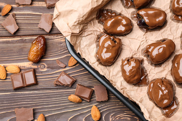 Sweet dried dates covered with chocolate on baking tray