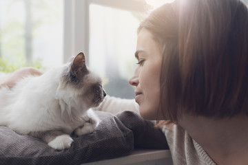 Woman petting her cat next to a window