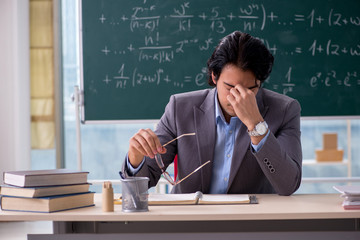Young handsome math teacher in classroom 