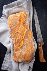 Traditionelles italienisches Ciabatta Bread als Draufsicht auf einem alten schwarzen Board mit...