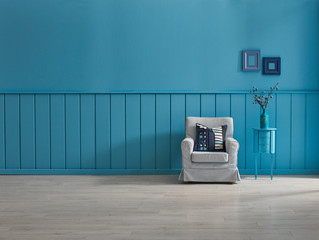 Blue wooden wall decoration with blue armchair pillow, frame and vase of plant.
