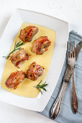 Baked pork tenderloin wrapped in bacon and served in a cheese sauce with rosemary