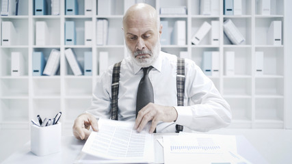 Disappointed businessman reading a multi-page report
