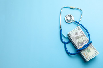 Stack of cash dollars and stethoscope on blue background. The concept of medical strechevka or...