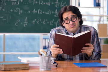 Young funny math teacher in front of chalkboard 