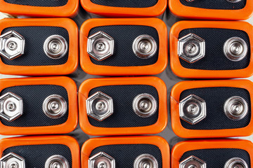 Background image of a large number of orange batteries, standing in several rows
