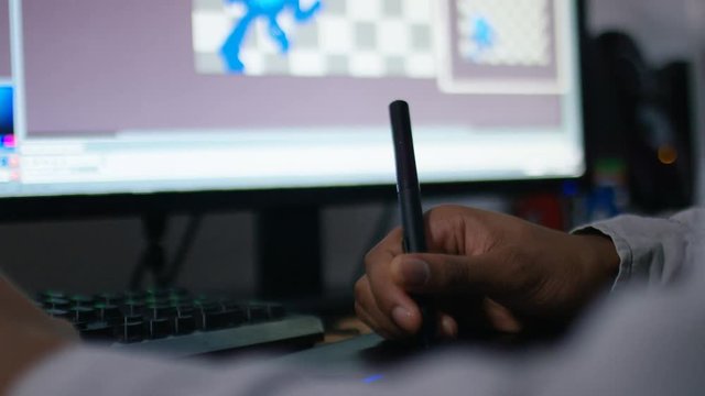 Hand of a digital animator at work using pen and tablet to create on a screen
