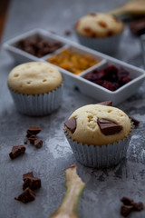 Freshly made vanilla muffins with dried fruit, raisins, cranberries and chocolate. As well as sliced banana. copy space