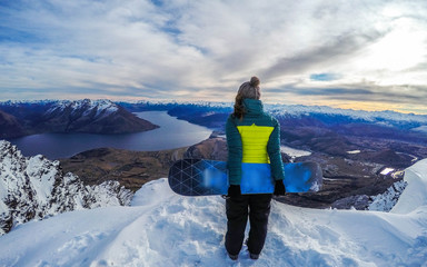 Winter sport activity.Woman holding snowboard, overlooking mountain landscape freedom, enjoying a...