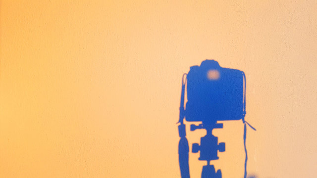 silhouette of camera reflex on the wall at sunset, concept of technology photography