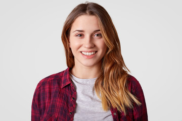 Close up shot of cheerful woman with long hair, toothy smile, has attractive appearance, wears...