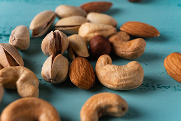 Assortment of nuts in wooden bowl on blue wooden table. Cashew, hazelnuts, almonds.