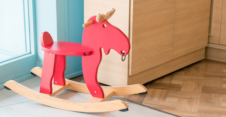 Red rocking horse toy for kid in home living room, cheerful riding stuff for children playing on...