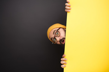 Funny man peeking out from behind yellow banner