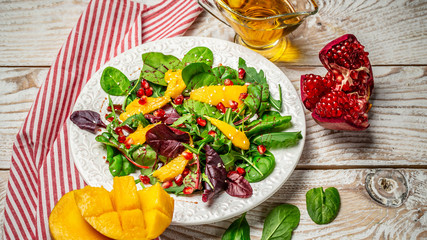 Plate with light dietary salad of arugula, mango and pomegranate. Clean eating, detox, vegetarian food concept