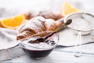 Fresh buttery croissants marmalade and oranges on kitchen table
