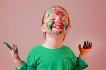 Portrait of very happy little child girl with children's makeup and painting colorful hands. Positive emotions concept. © zwiebackesser