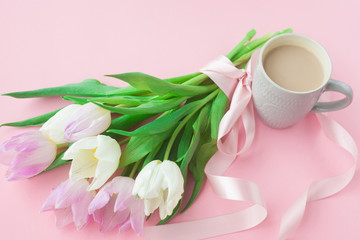 Obraz na płótnie Canvas Bouquet of tulips and a coffee cup on a pink pastel background. Wonderful spring breakfast on Mother's Day or Women. Flat lay. View top. Selective focus.